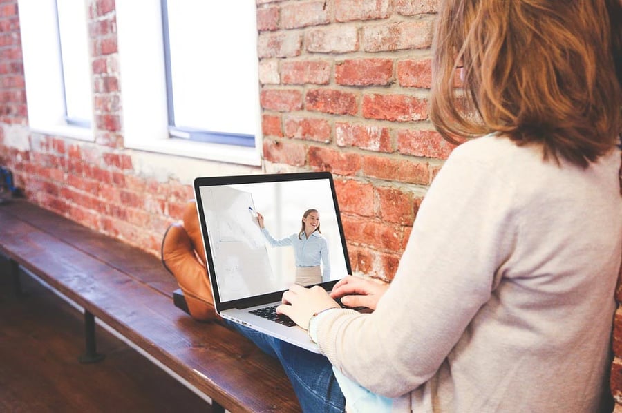 Woman watching a video feed of a class on her laptop